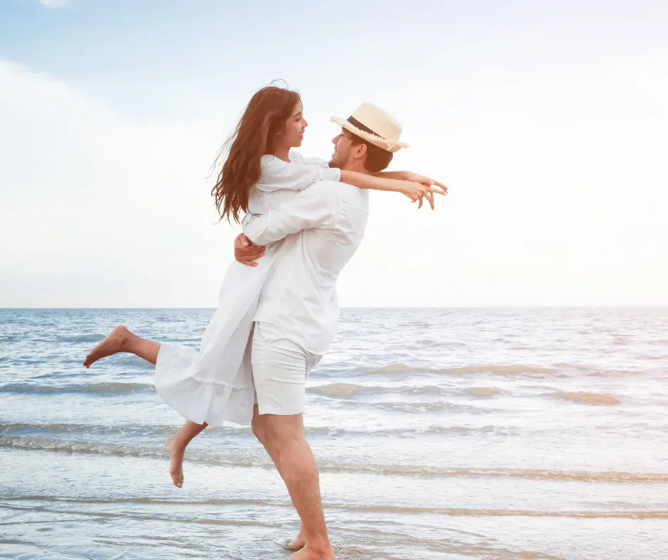 Organizzazione di viaggi Una coppia felice in abiti estivi balla sulla spiaggia al tramonto.