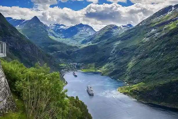 agente di viaggio Fiordo norvegese con montagne verdi e una nave da crociera che naviga attraverso le acque tranquille.