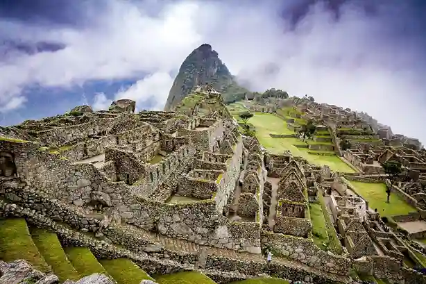 consulente di viaggio Le antiche rovine di Machu Picchu con il Huayna Picchu che si innalza sullo sfondo sotto un cielo nuvoloso.