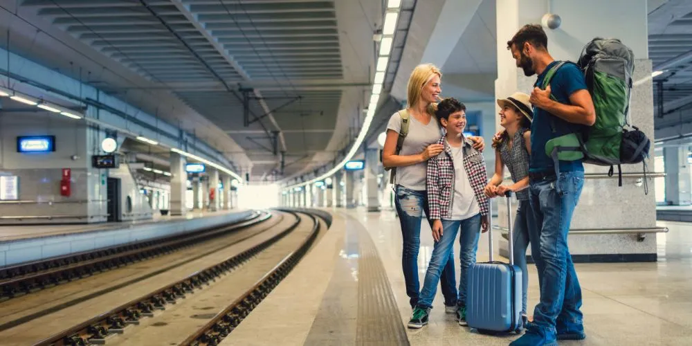 Famiglia sorridente pronta per una vacanza in treno alla stazione ferroviaria
